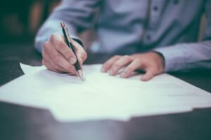 Persona revisando y firmando documentación sobre una mesa